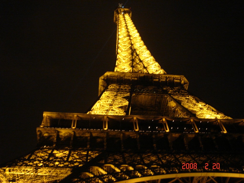 L atour Eiffel illuminée en jaune de nuit.
